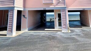 En bygning med flere etager, rosa facade, garageindgang og udsigt til vandet.
