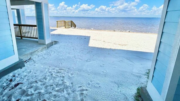A beach view from a covered porch with a wooden deck and a view of the ocean. - Serenita Ora: Quiet Waterfront Unit with 2 Kayaks! (Pensacola)