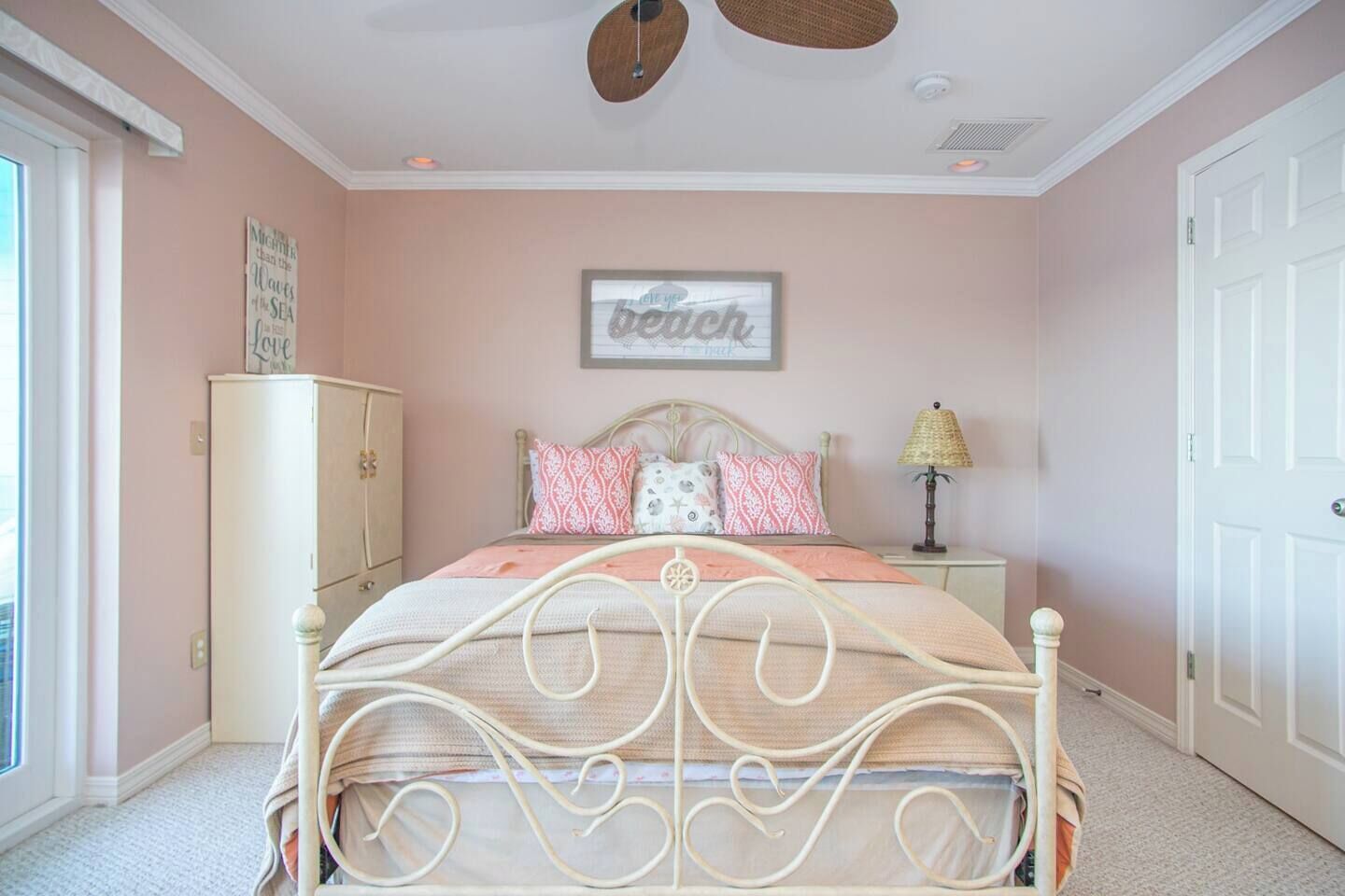A bedroom with a bed, a nightstand, a lamp, a wardrobe, and a wall with a sign.