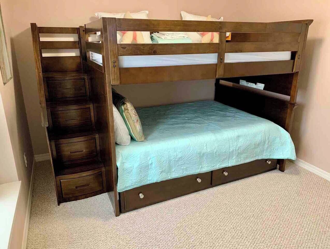 A bunk bed with a lower bunk, a ladder, and a storage drawer.
