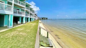 Un hôtel situé en bord de mer, doté de nombreux balcons, d’une pelouse verdoyante et d’une promenade en bois menant à la plage.