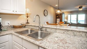 A kitchen with granite countertops, stainless steel sink, and pendant lighting. - Bay Paradise: Paddle Boards, Kayaks, & Waterfront! (Pensacola)