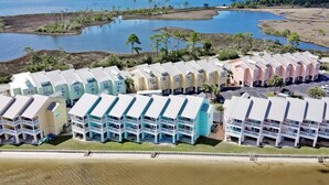 A beachfront hotel with multiple-story buildings, a sandy beach, and a large body of water in the background. - Bay Paradise: Paddle Boards, Kayaks, & Waterfront! (Pensacola)