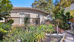 A house with a curved roof, surrounded by a garden with various plants and a metal fence. - 21 Cooloola Drive - Rainbow Beach (Rainbow Beach)