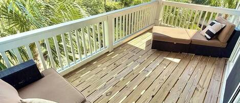 A wooden deck with a cushioned seating area and a white railing.
