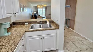A kitchen with granite countertops, white cabinets, and a double sink.