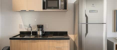 A modern kitchen with a stainless steel refrigerator, a microwave, and a coffee maker on the countertop.