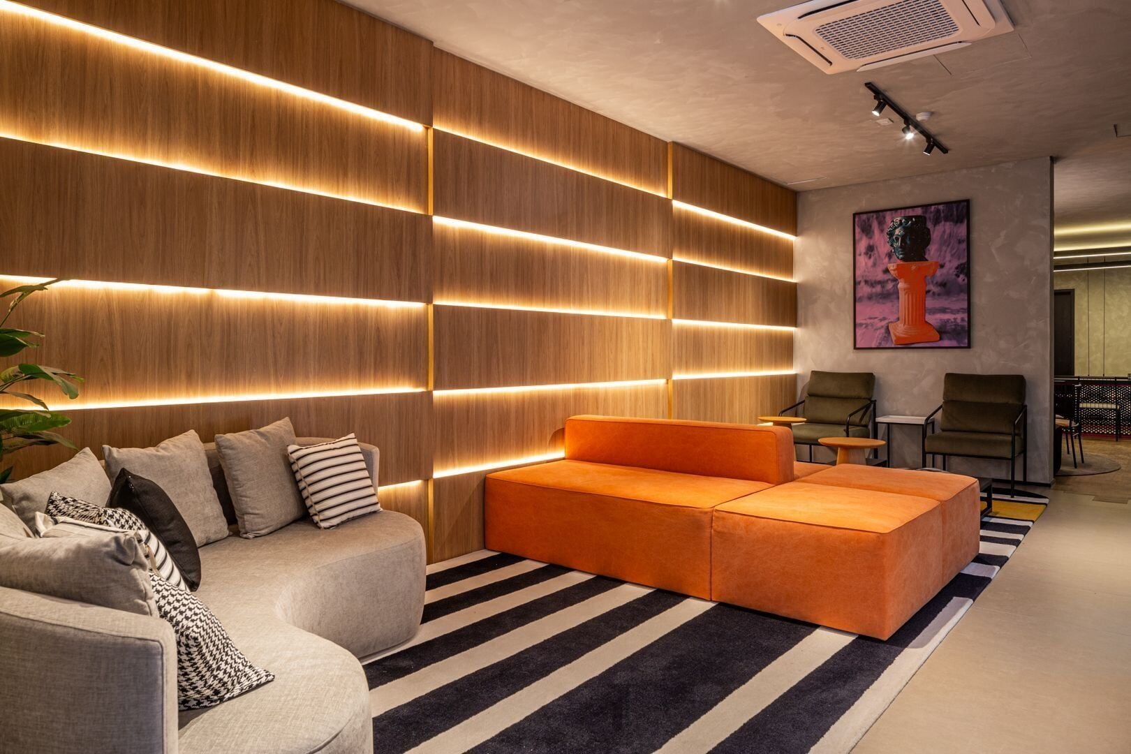 A modern living room with a sectional sofa, a grey armchair, and a striped rug.