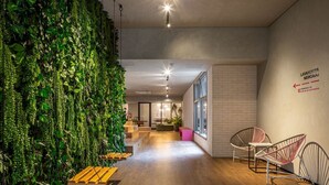 Un interior moderno con una pared verde, bancos de madera y sillas de metal.
