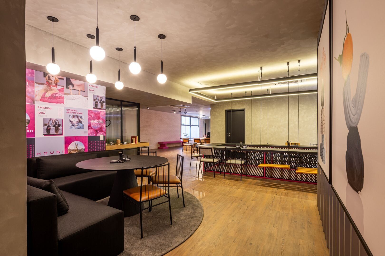 A modern interior with a round dining table, black sofas, and a bar area with stools.