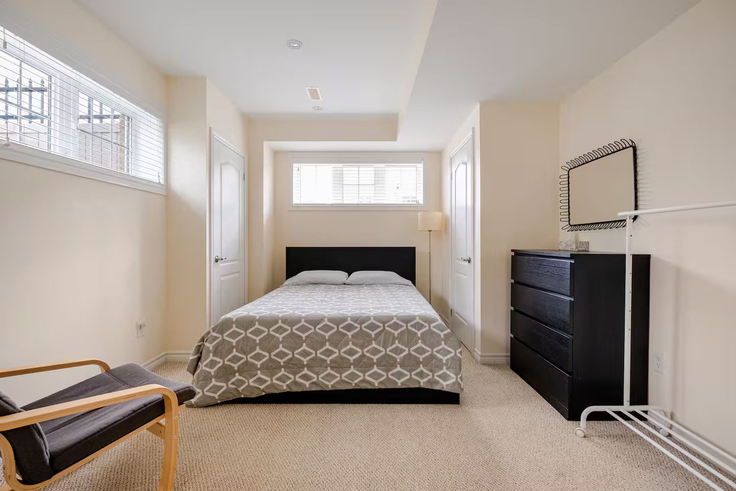 Een slaapkamer met een bed, een dressoir, een stoel en een raam met jaloezieën.