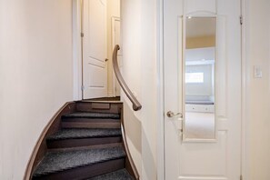 Eine Treppe mit Teppichbelag und einem Metallgeländer, die zu einer weißen Tür führt.
