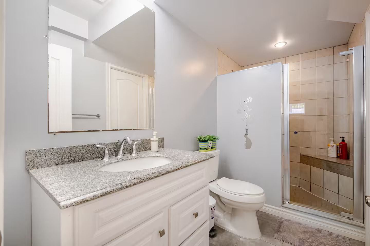 A bathroom with a double sink vanity, a toilet, and a shower area.
