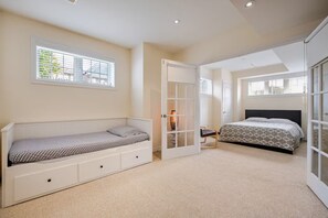 Une chambre avec un lit superposé, un canapé-lit, une armoire et une grande fenêtre.