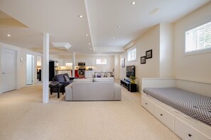 A modern living room with a sofa, a TV, and a dining area. - Spacious 2 BR, 3 beds, sleeps 6, kitchen, laundry (Richmond Hill)