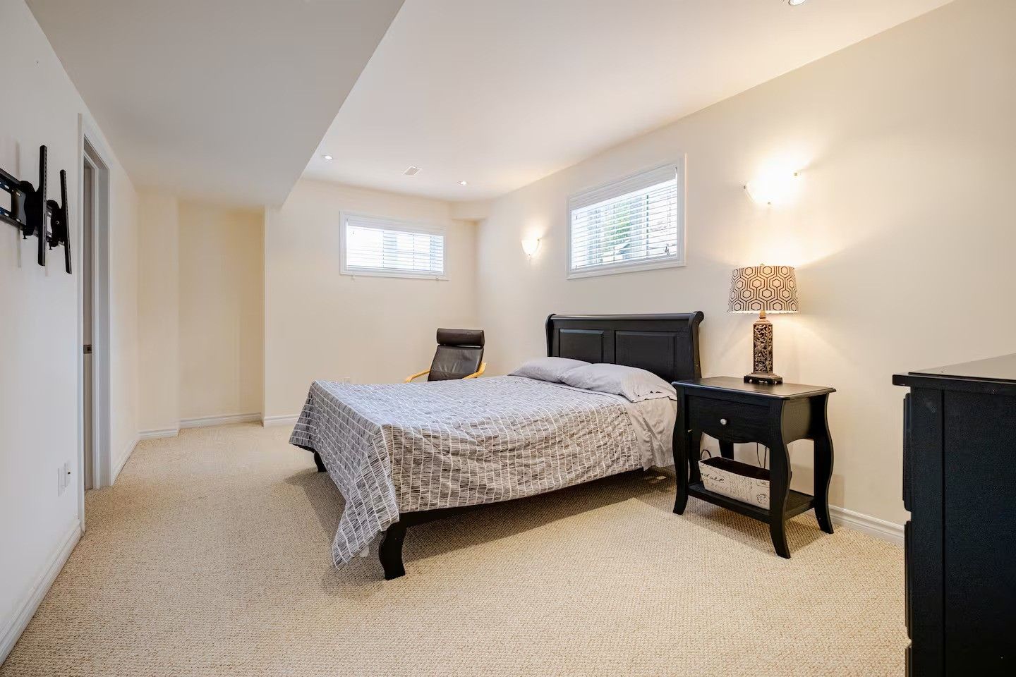 A bedroom with a bed, a chair, a nightstand, and a dresser.