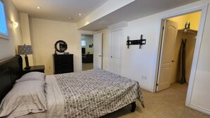 A bedroom with a bed, dresser, and a wall-mounted TV. - Spacious 2 BR, 3 beds, sleeps 6, kitchen, laundry (Richmond Hill)
