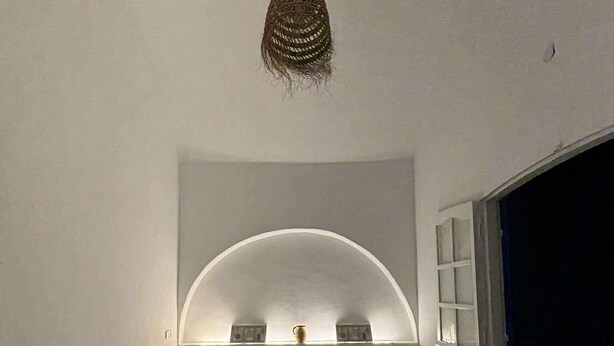 A bedroom with a bed, a hanging light fixture, and a window.