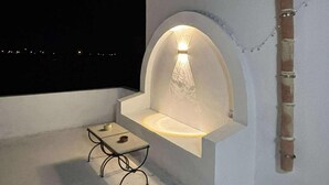 A rooftop terrace with a built-in seating area and a wall-mounted light fixture.