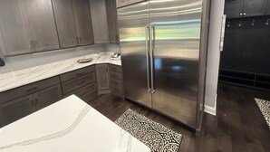 Eine moderne Küche mit dunklen Holzschränken, einem Edelstahlkühlschrank und einer Marmorarbeitsplatte.