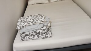 A single bed with a striped headboard, two pillows, and a folded blanket. - Bel air flat (Villeneuve-Loubet)