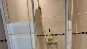 A shower stall with a glass door, a handheld showerhead, and a soap dispenser on the wall. - Bel air flat (Villeneuve-Loubet)