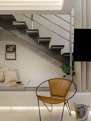 A modern interior with a staircase, a sofa, a chair, and a flat-screen TV. - Box 150 (Joao Pessoa)