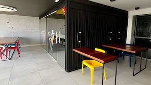 Un interior moderno con un separador de vidrio, una mesa de madera y sillas coloridas.