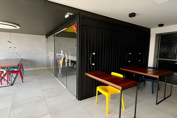 A modern interior with a glass partition, a wooden table, and colorful chairs.