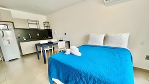 Habitación de hotel con cama, escritorio y kitchenette.