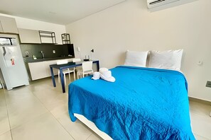 A hotel room with a bed, a desk, and a kitchenette. - Box 150 (Joao Pessoa)