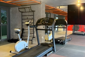 A gym with stationary bikes, a treadmill, and a wall-mounted exercise machine. - Box 150 (Joao Pessoa)