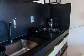 A modern kitchen with a black countertop, stainless steel sink, and a coffee maker.