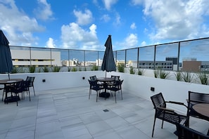 Une terrasse sur le toit avec des sièges en plein air, une vue sur le paysage urbain et un ciel dégagé.