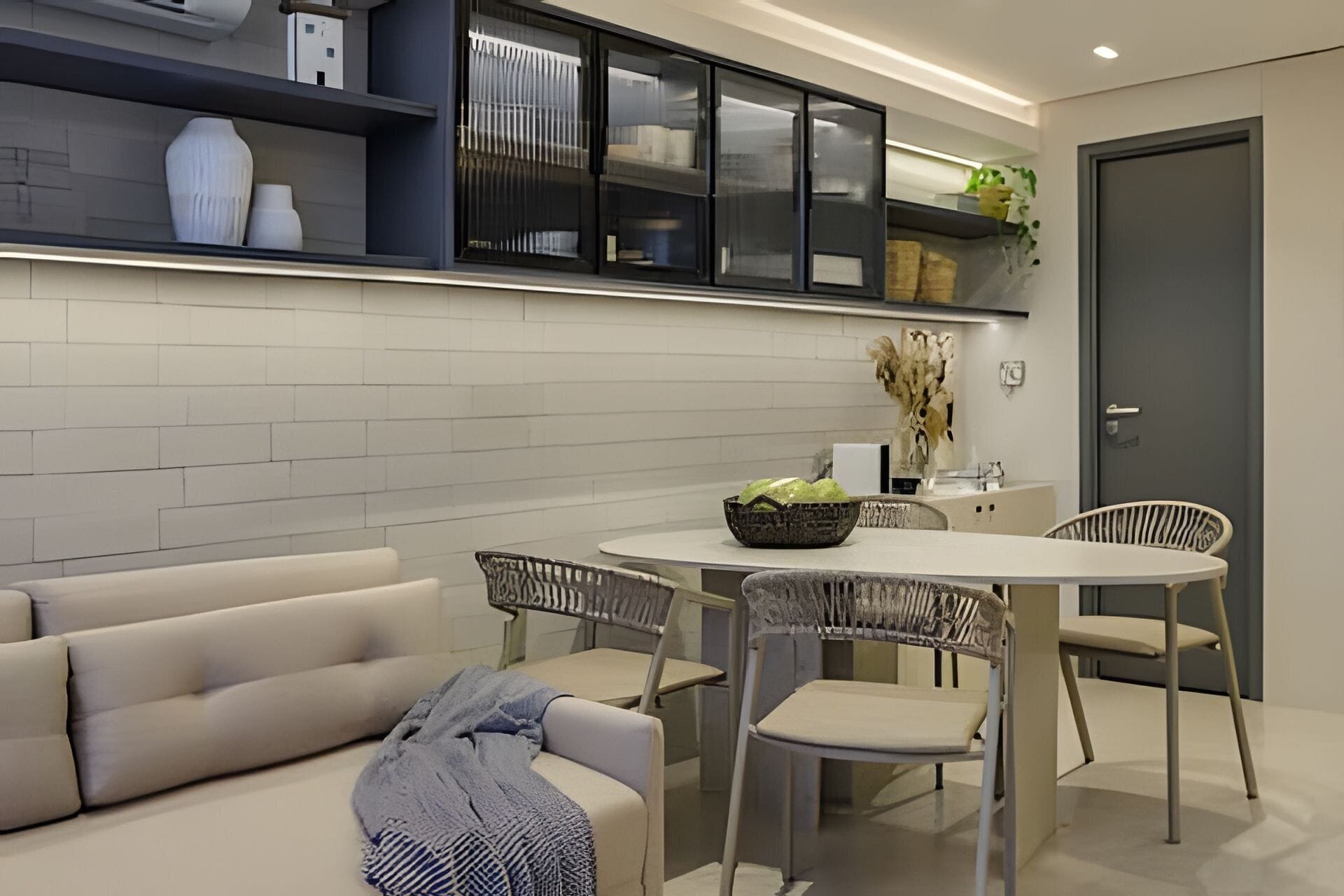 A modern kitchen with white cabinets, a dining table with chairs, and a sofa.