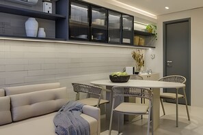 Een moderne keuken met witte kastjes, een eettafel met stoelen en een bank.