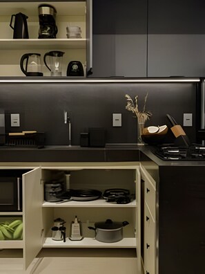 Een moderne keuken met inbouwapparatuur, een koffiezetapparaat, een waterkoker en een pan op het aanrecht.