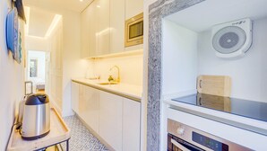 A modern kitchen with white cabinets, a stainless steel Bosch coffee maker, a microwave, and a built-in oven. - GuestReady - Relaxing place in Lisbon (Lisbon)