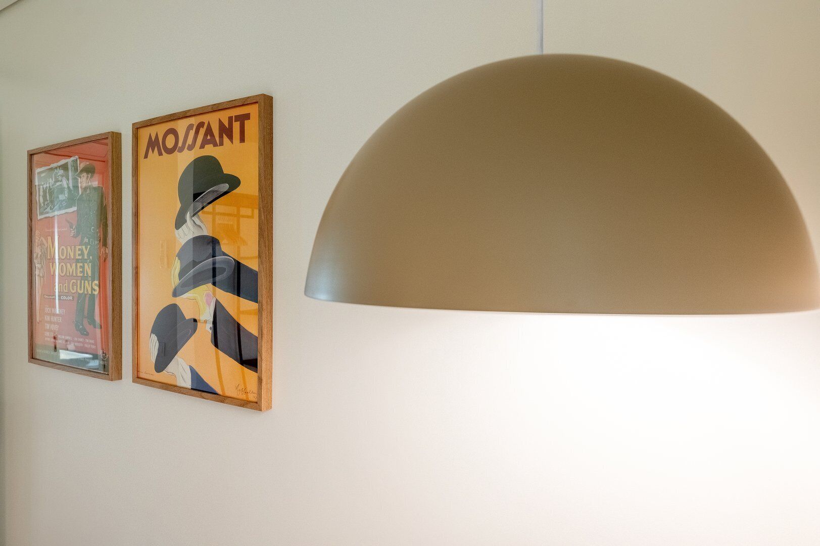 Two framed posters on a wall and a large, semi-circular ceiling lamp.