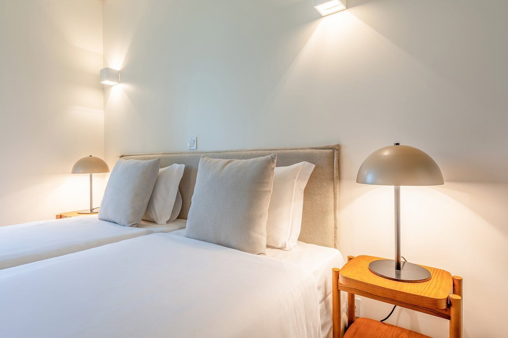 A hotel room with two beds, a wooden headboard, and two bedside lamps.