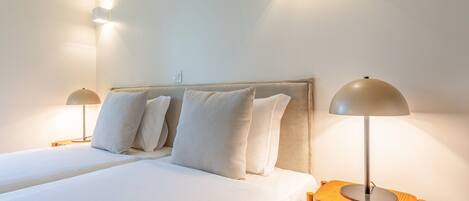 A hotel room with two beds, a wooden headboard, and two bedside lamps.