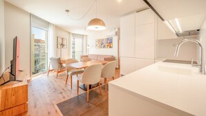 A modern kitchen with a dining area, a large window, and a view of a building outside.