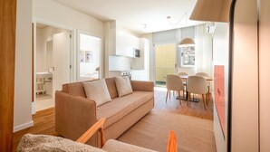 Una sala moderna con un sofá, una mesa de comedor con sillas y una cocina al fondo.