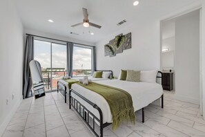 A modern bedroom with a large bed, a ceiling fan, and a view of the city through large windows. - Dallas City Views  (Dallas)
