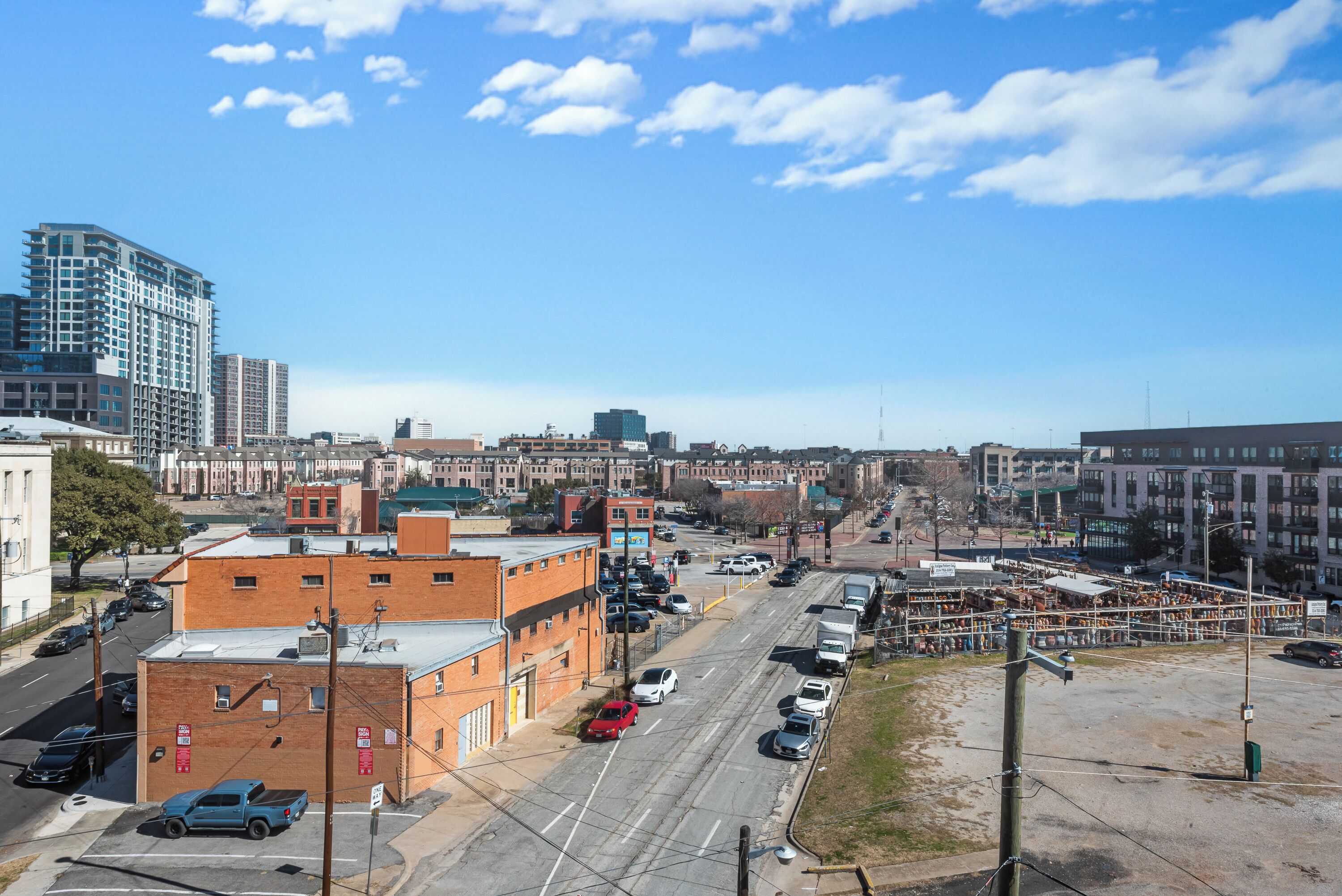 A cityscape with a mix of modern and older buildings, a wide street, and a clear sky.