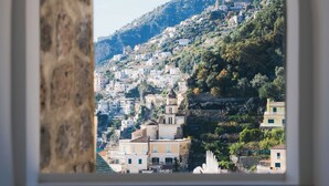Une vue à travers une porte en arc d’une ville côtière, avec des bâtiments construits sur une colline.