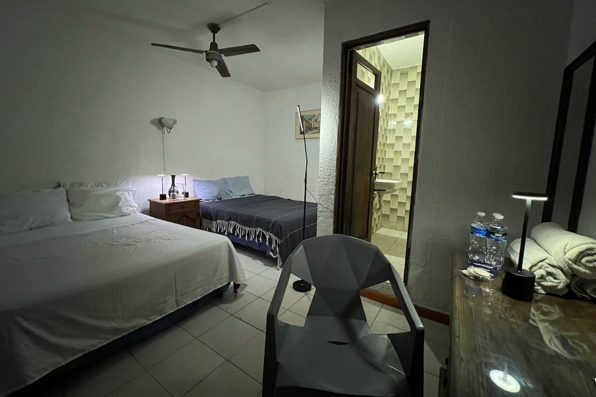 A bedroom with a bed, bedside table, lamp, chair, and a door leading to a bathroom.