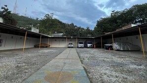 A parking area with numbered garage doors, a concrete pathway, and a gravel surface. - Marqués 100 (Oaxaca)