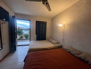 A bedroom with two beds, a ceiling fan, a window with curtains, and a wall-mounted light fixture. - Marqués 100 (Oaxaca)