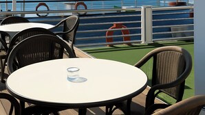 A deck with outdoor seating, a view of the sea, and a sailboat in the distance. - Nile Cruise Royal Queen 2 Every Wednesday from Aswan 3 nights and every Saturday from Luxor 4 nights (Aswan)